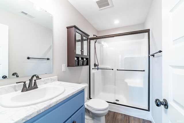 bathroom featuring a shower stall, wood finished floors, vanity, and toilet