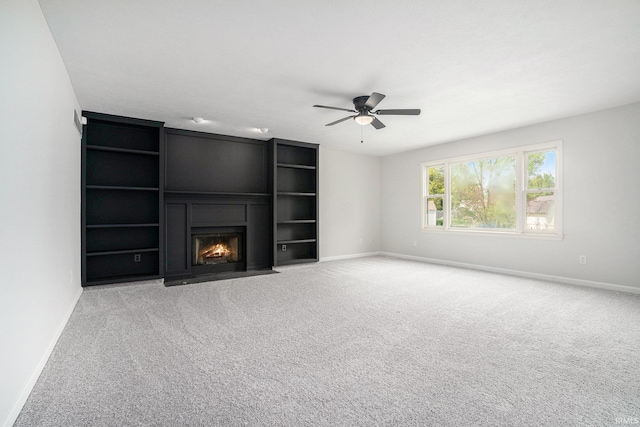 unfurnished living room with baseboards, ceiling fan, carpet floors, and a fireplace