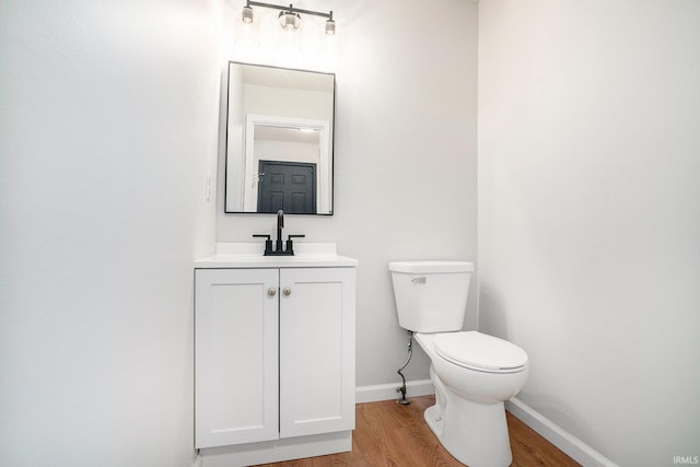 bathroom featuring wood finished floors, toilet, baseboards, and vanity