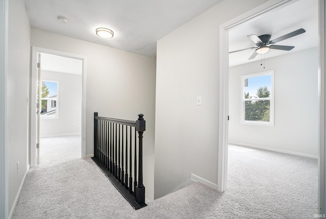 corridor featuring an upstairs landing, carpet flooring, and baseboards