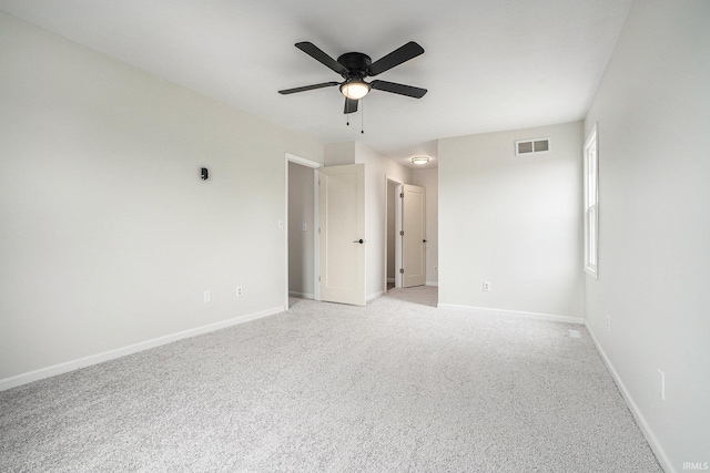 spare room featuring ceiling fan, light colored carpet, and baseboards