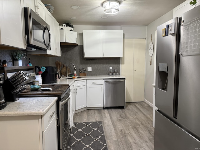 2823 Hillside Dr, Bedford, IN 47421 - kitchen with appliances with stainless steel finishes, a sink, light countertops, decorative backsplash, and white cabinets
