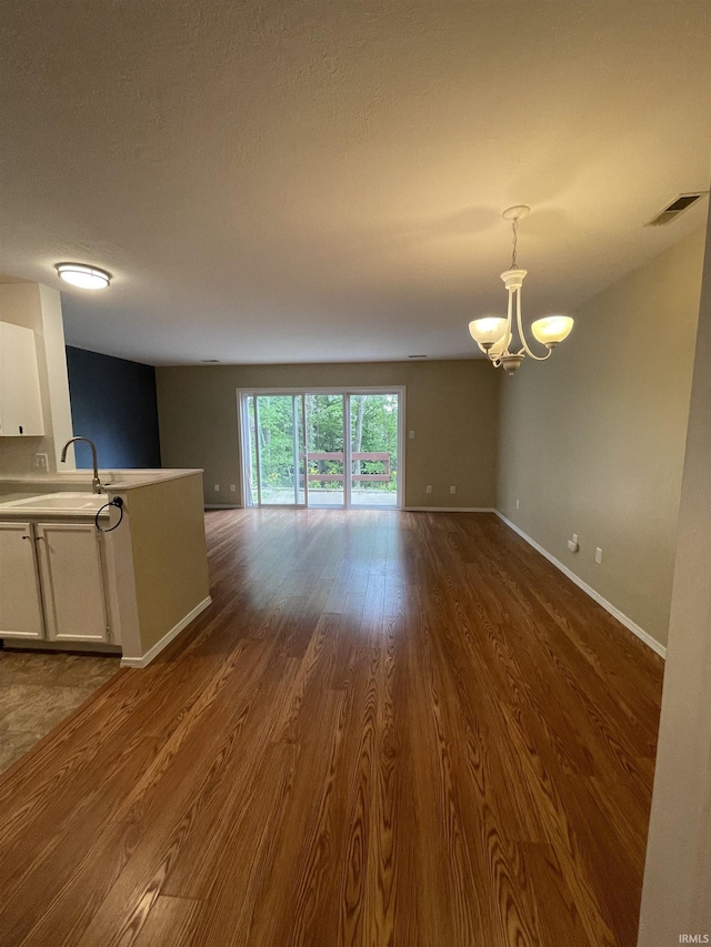 620 Bayberry Ct, Bloomington, IN 47401 - unfurnished living room featuring a chandelier, a sink, dark wood-style floors, and baseboards