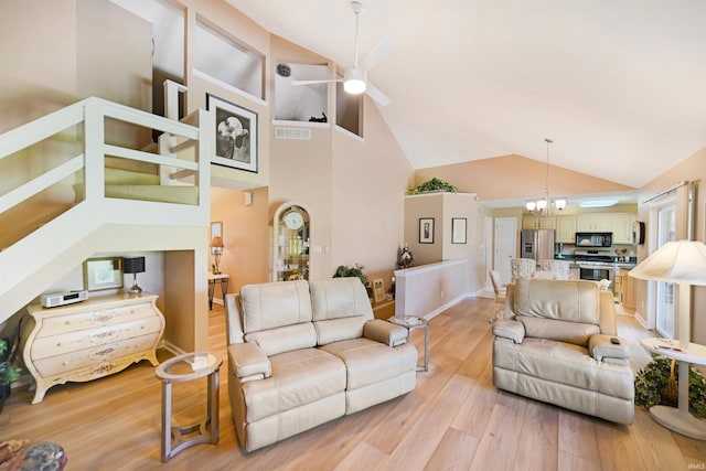 living room featuring ceiling fan, light wood-style flooring, high vaulted ceiling, baseboards, and a chandelier