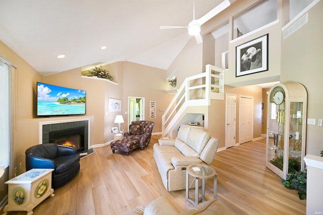 living room featuring high vaulted ceiling, a tiled fireplace, wood finished floors, ceiling fan, and recessed lighting