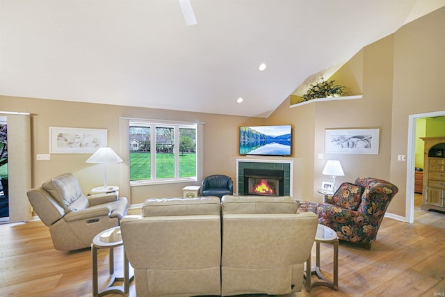 living area with light wood-style floors, a tile fireplace, lofted ceiling, recessed lighting, and baseboards