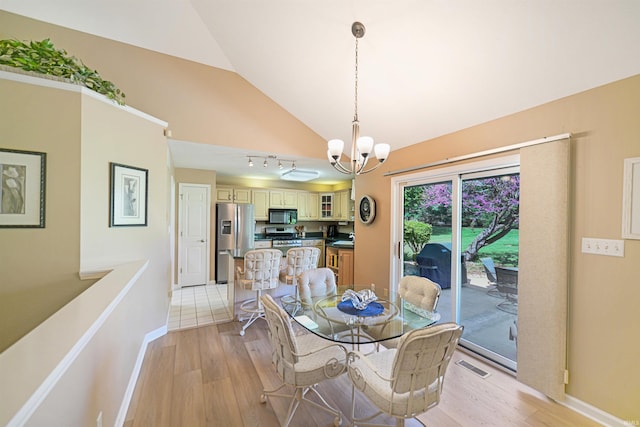 dining room featuring a chandelier, vaulted ceiling, light wood-style floors, and baseboards