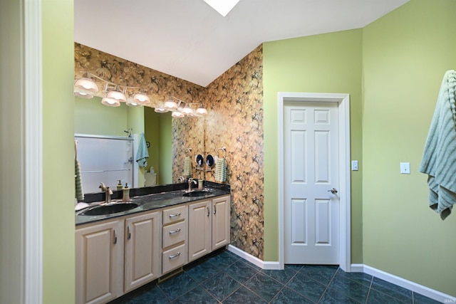 bathroom with baseboards, double vanity, lofted ceiling, and tile patterned flooring
