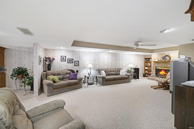 carpeted living room featuring wallpapered walls, a ceiling fan, and a fireplace