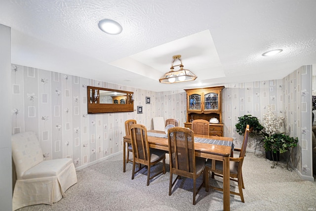 dining room with light colored carpet, a textured ceiling, baseboards, and wallpapered walls