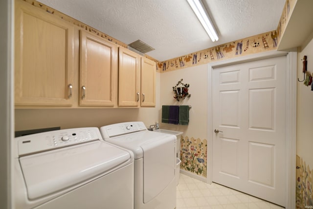 laundry room featuring cabinet space, washing machine and dryer, light floors, a textured ceiling, and baseboards