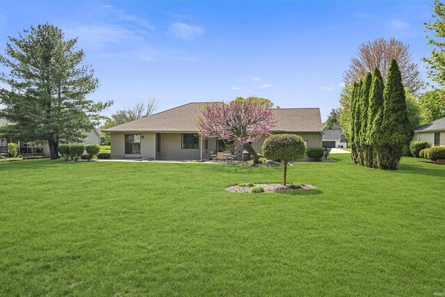 rear view of property featuring a lawn, a patio area, and roof with shingles