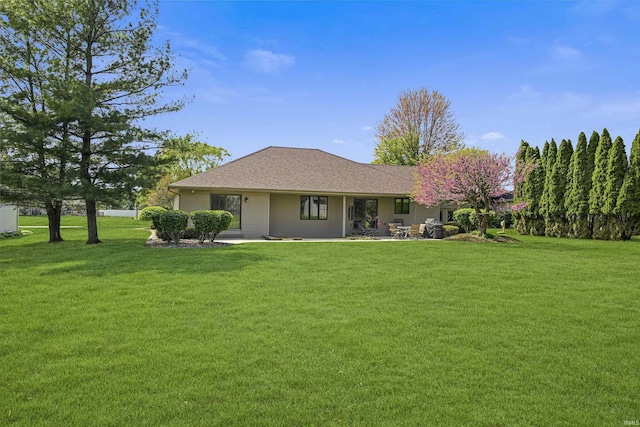 back of property with a yard, a patio area, and roof with shingles