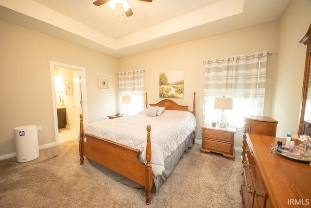3417 S Tulip Ave, Bloomington, IN 47403 - bedroom featuring light carpet, a raised ceiling, baseboards, ensuite bathroom, and a ceiling fan
