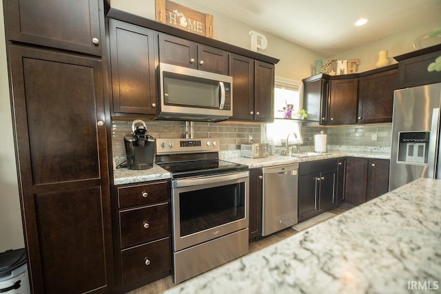 3417 S Tulip Ave, Bloomington, IN 47403 - kitchen with stainless steel appliances, a sink, dark brown cabinetry, tasteful backsplash, and light stone counters