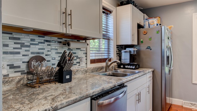 208 S Ohio St, Chandler, IN 47610 - kitchen with appliances with stainless steel finishes, a sink, white cabinetry, and tasteful backsplash