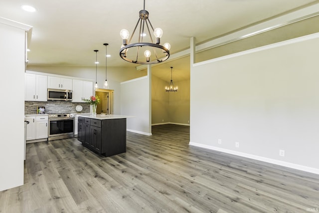 kitchen featuring stainless steel appliances, a chandelier, vaulted ceiling, decorative backsplash, and a center island