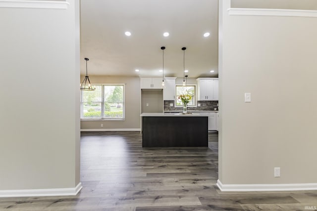 kitchen with white cabinetry, baseboards, a center island, dark wood finished floors, and decorative backsplash