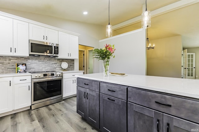 kitchen with stainless steel appliances, light countertops, white cabinets, backsplash, and light wood-style flooring