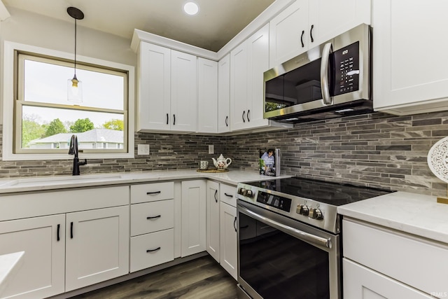 kitchen with stainless steel appliances, a sink, tasteful backsplash, white cabinets, and dark wood-type flooring
