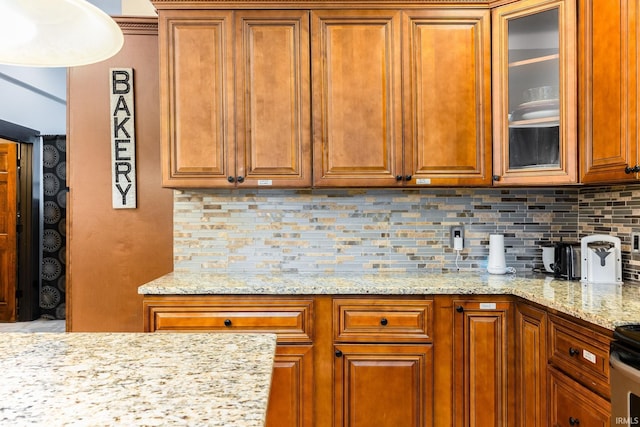 1026 N Michigan St, South Bend, IN 46617 - kitchen with backsplash, brown cabinetry, glass insert cabinets, and light stone countertops