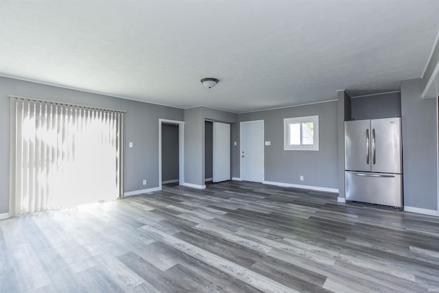 unfurnished living room with baseboards and dark wood-type flooring