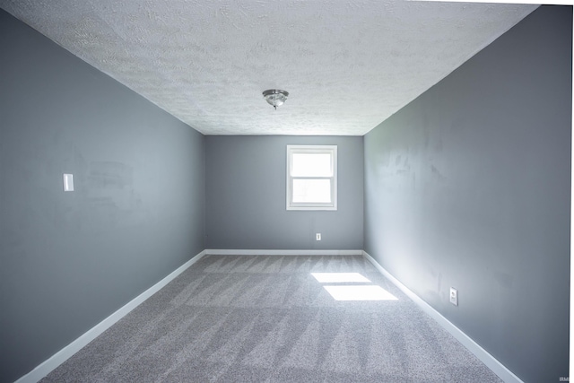 empty room with a textured ceiling, carpet floors, and baseboards