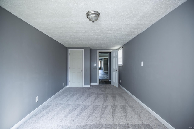 unfurnished bedroom featuring carpet floors, baseboards, and a textured ceiling