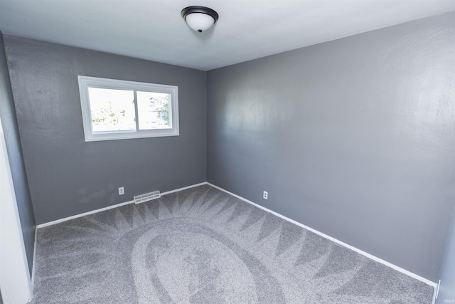 unfurnished room with dark carpet and baseboards