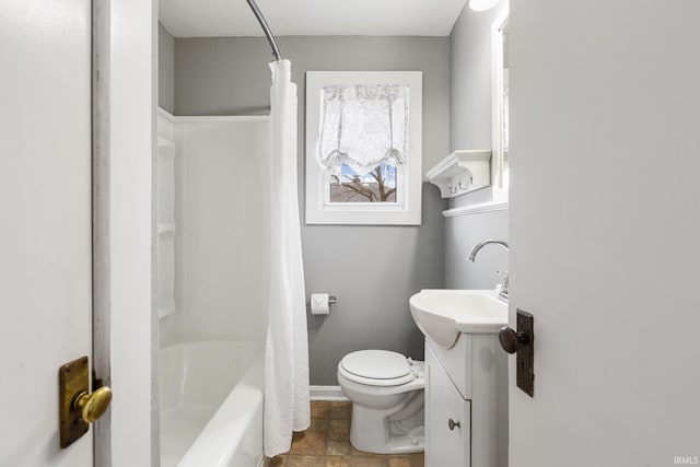 bathroom with vanity, toilet, baseboards, shower / tub combo with curtain, and stone finish flooring