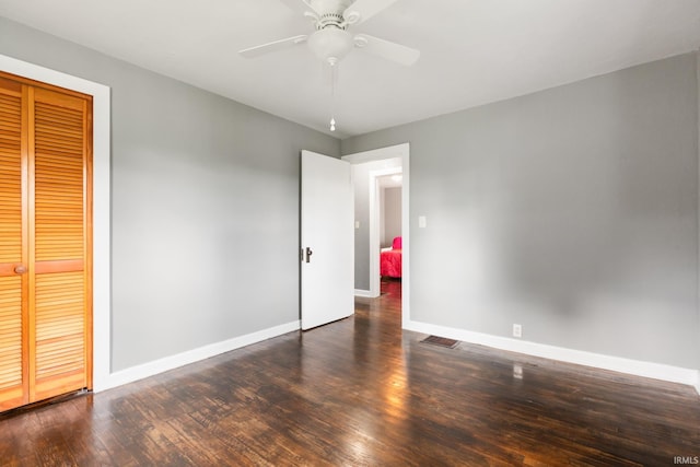 unfurnished bedroom featuring baseboards, wood finished floors, a closet, and ceiling fan