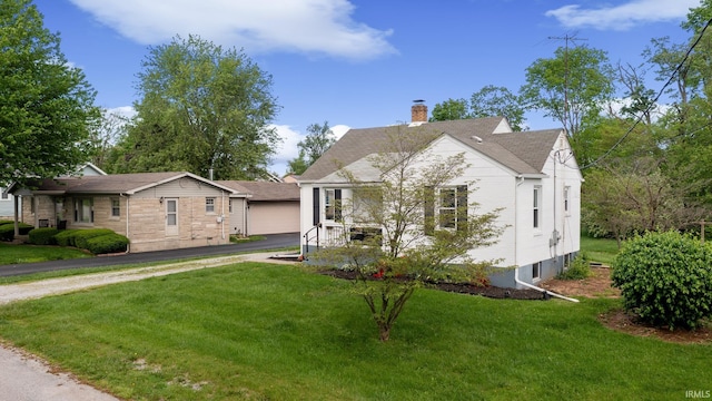 view of front of home featuring a chimney, a front yard, a garage, and roof with shingles