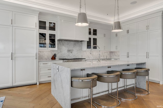 202 W Berry St Unit 810, Fort Wayne, IN 46802 - kitchen featuring a sink, white cabinets, backsplash, glass insert cabinets, and a kitchen bar