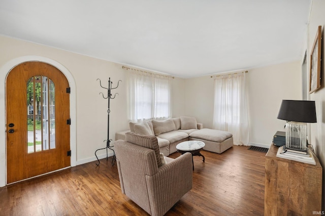 living area with arched walkways, wood finished floors, and baseboards