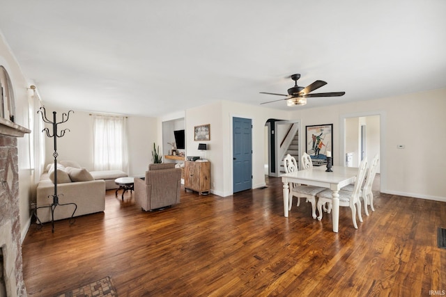 dining room featuring wood finished floors, a ceiling fan, stairway, and baseboards