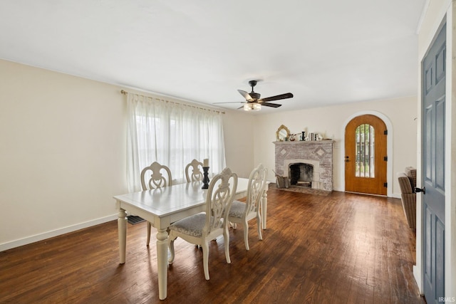 dining space with a brick fireplace, dark wood-type flooring, and plenty of natural light