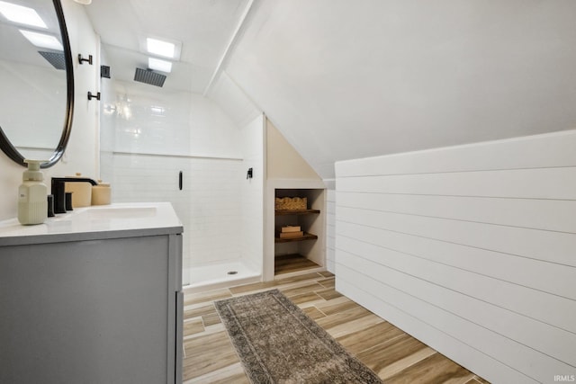 bathroom featuring a stall shower, wood finished floors, vanity, and lofted ceiling