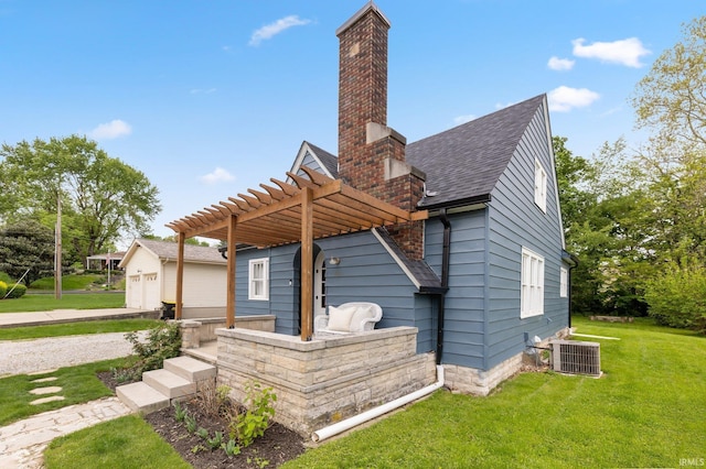 back of property with a chimney, central AC unit, a yard, a pergola, and a shingled roof