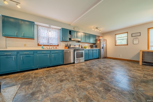 521 S Riverside Dr, Winamac, IN 46996 - kitchen with appliances with stainless steel finishes, a sink, under cabinet range hood, tasteful backsplash, and light countertops