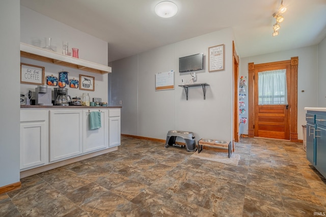 521 S Riverside Dr, Winamac, IN 46996 - kitchen with stone finish flooring, white cabinets, open shelves, and baseboards