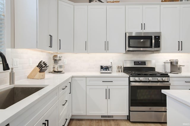 104 Lavender Ct, New Carlisle, IN 46552 - kitchen featuring appliances with stainless steel finishes, a sink, white cabinetry, decorative backsplash, and light stone countertops