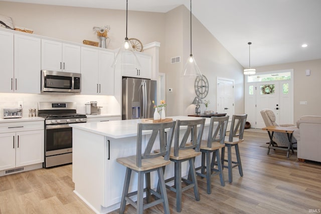 104 Lavender Ct, New Carlisle, IN 46552 - kitchen with appliances with stainless steel finishes, light wood-style floors, a center island, light countertops, and decorative backsplash