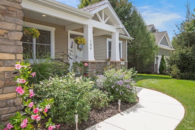 104 Lavender Ct, New Carlisle, IN 46552 - doorway to property featuring stone siding, a yard, and covered porch