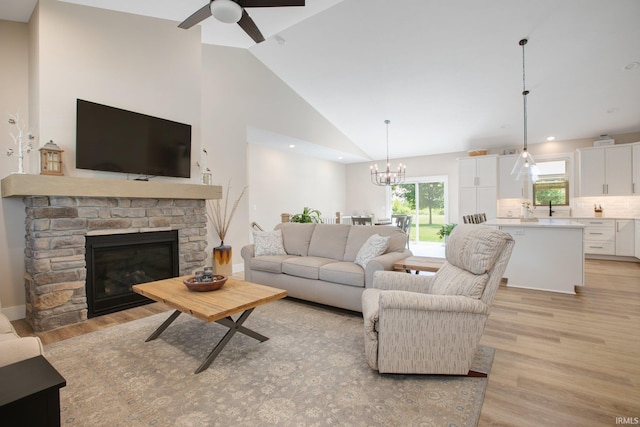 104 Lavender Ct, New Carlisle, IN 46552 - living room featuring light wood-type flooring, a stone fireplace, ceiling fan, a chandelier, and high vaulted ceiling