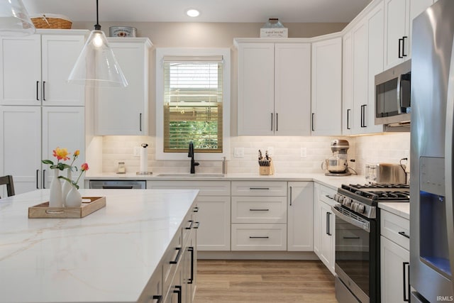 104 Lavender Ct, New Carlisle, IN 46552 - kitchen featuring stainless steel appliances, a sink, white cabinets, pendant lighting, and light wood finished floors