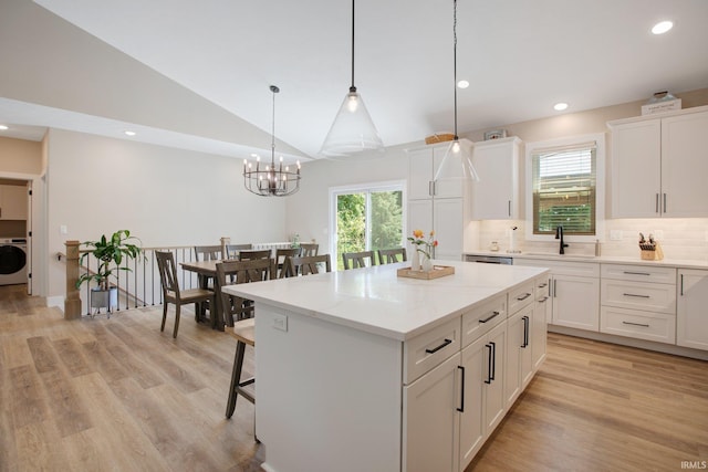 104 Lavender Ct, New Carlisle, IN 46552 - kitchen with washer / dryer, white cabinets, a kitchen island, decorative backsplash, and a chandelier