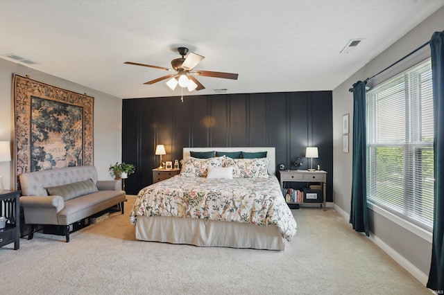bedroom featuring multiple windows, light colored carpet, a ceiling fan, and baseboards