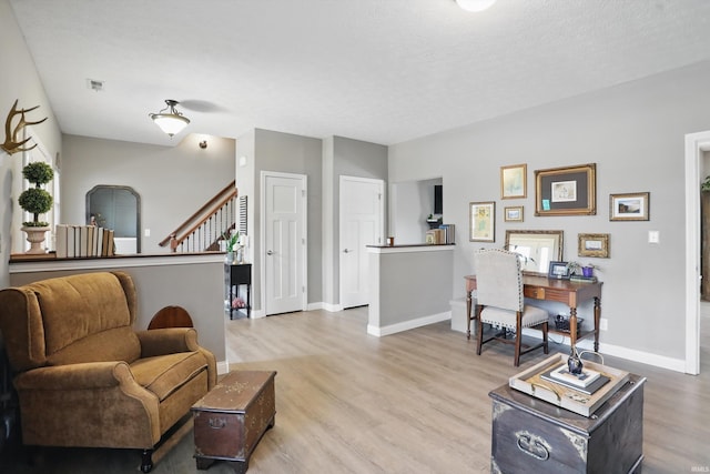 living room with light wood-style floors, baseboards, and stairway