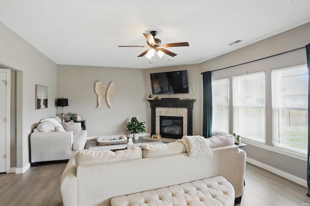 living room featuring wood finished floors, a ceiling fan, healthy amount of natural light, and baseboards