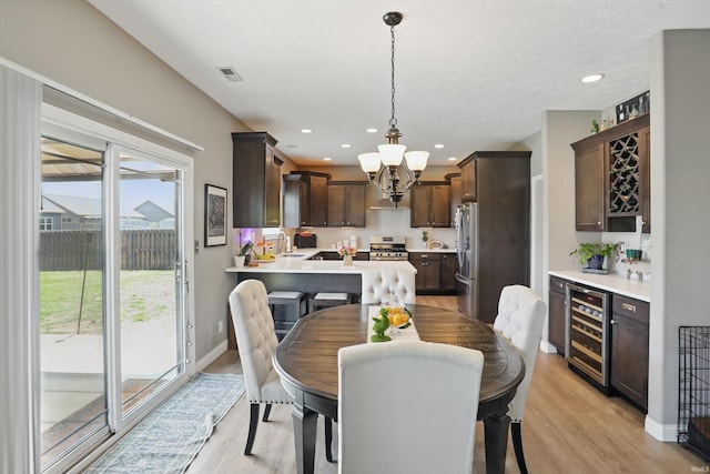 dining room featuring wine cooler, light wood-style floors, a chandelier, baseboards, and recessed lighting